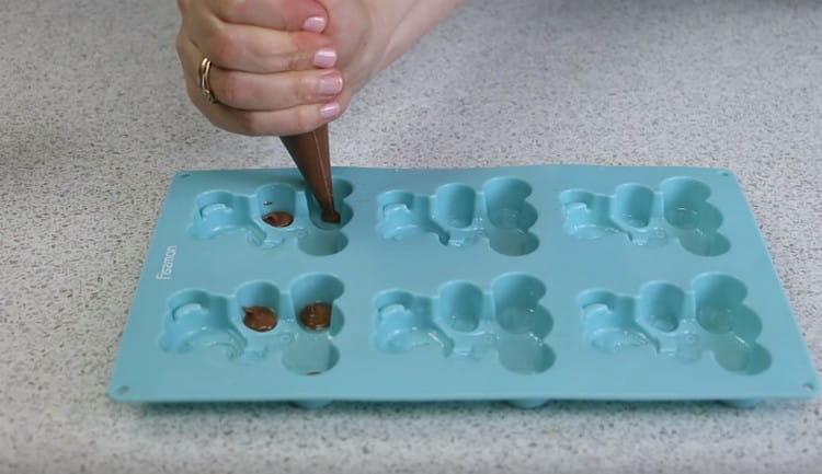 Squeeze the chocolate dough into the form where the teddy bear’s legs will be.