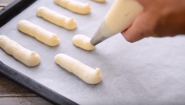 We send the dough into a pastry bag and squeeze thin long fingers onto a baking sheet covered with parchment.