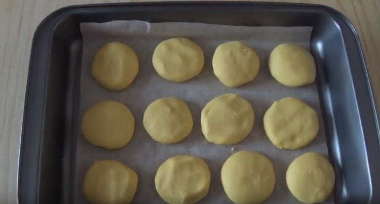 Cubra la bandeja para hornear con papel para hornear y ponga galletas sobre ella.