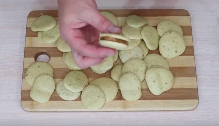 We take two cookies, grease them with boiled condensed milk and combine.