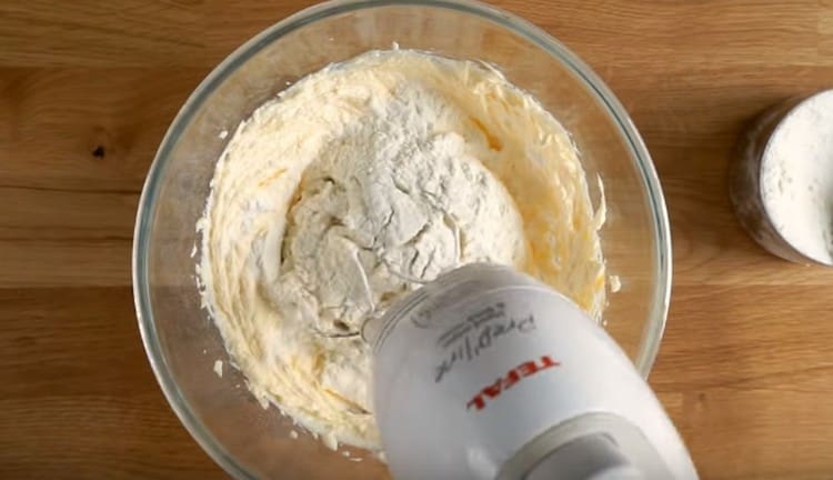 Postepeno dodajte brašno u tijesto, miješajući ga mikserom.