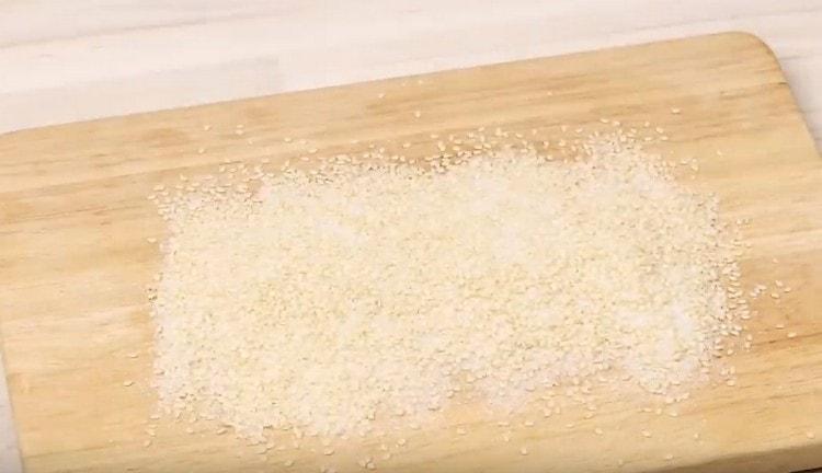 Versez un mélange de sucre et de graines de sésame sur une planche, à niveau.