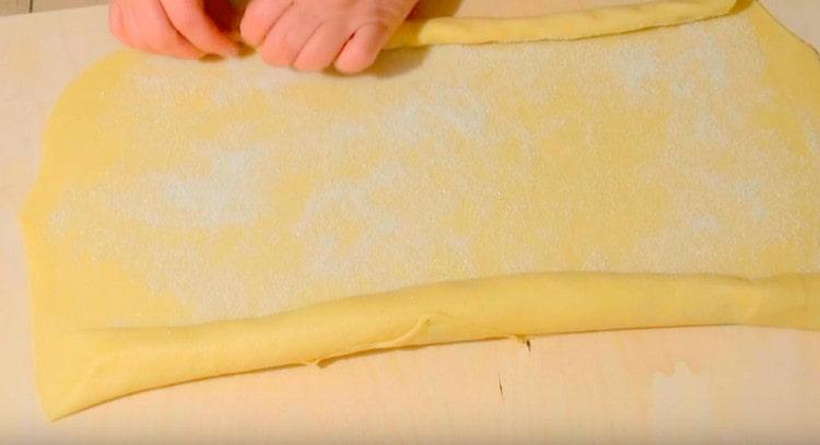 Starting from opposite edges, roll the dough into a roll until the middle.