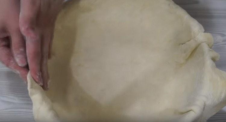 Most of the dough is placed in a baking dish sprinkled with flour.