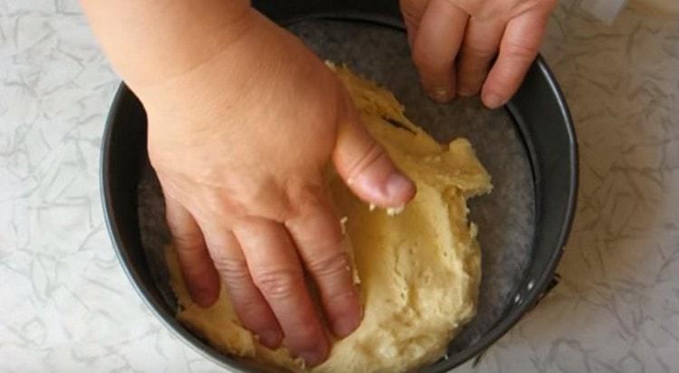 With a wet hand, we distribute the dough into a baking dish.