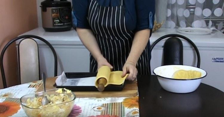 À l'aide d'un rouleau à pâtisserie, transférer une couche de pâte sur une plaque à pâtisserie recouverte de papier sulfurisé.