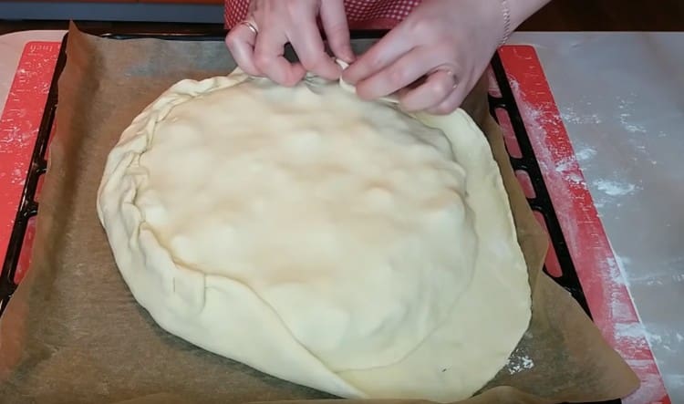 Roll out the second piece of dough, cover it with a pie and pinch the edges.