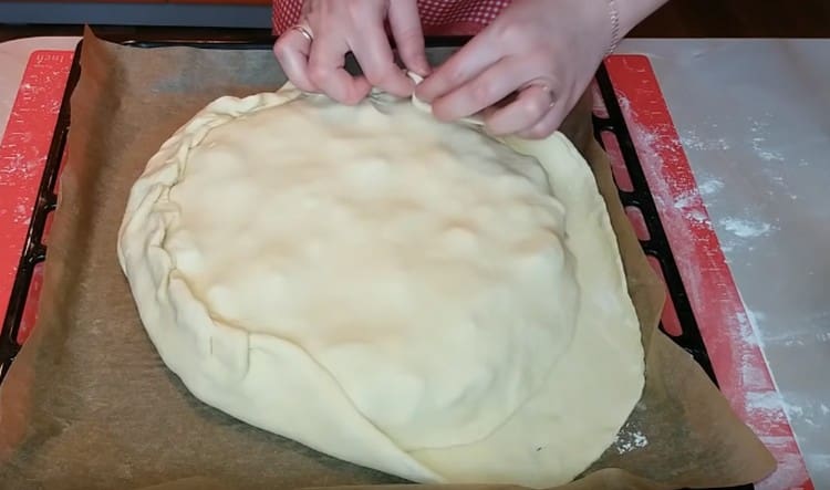 Estire la segunda pieza de masa, cúbrala con un pastel y pellizque los bordes.