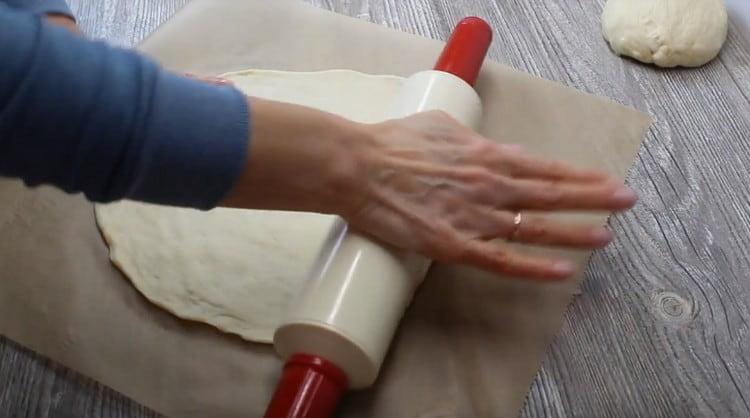 diviser la pâte en deux parties identiques et les enrouler légèrement sur une feuille de papier sulfurisé.