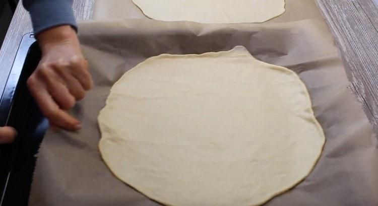 Avec le parchemin, transférer la pâte sur une plaque à pâtisserie.