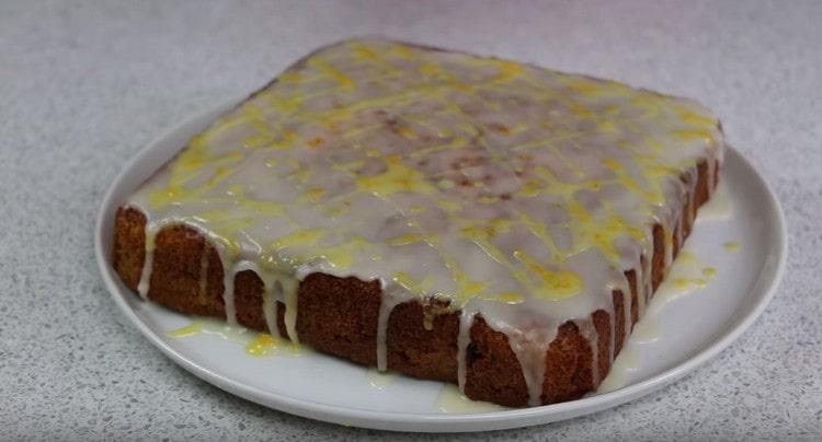 Verser le gâteau aux carottes avec du glaçage blanc et jaune.