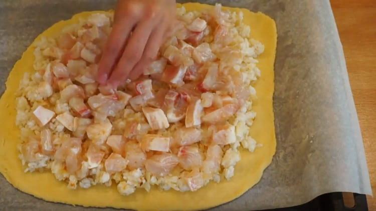 On étale une couche de pâte sur une plaque de cuisson, on nivelle le riz avec des oignons et on étale le poisson.