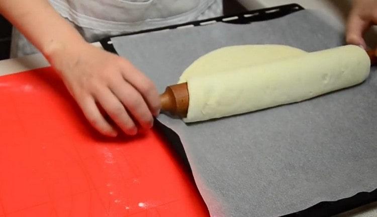 Con un rodillo, transfiera la masa a una bandeja para hornear.