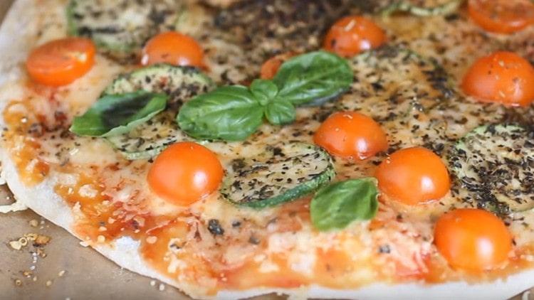 Une pizza végétarienne prête peut être décorée avec des feuilles de basilic.