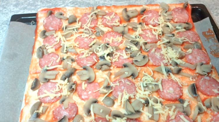 Espolvorea pizza con queso rallado.
