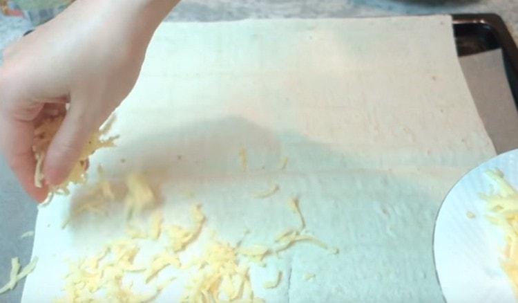 Espolvorea pan de pita con una porción de queso rallado.