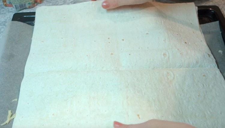 On top of the cheese, lay out another sheet of pita bread and gently press it.