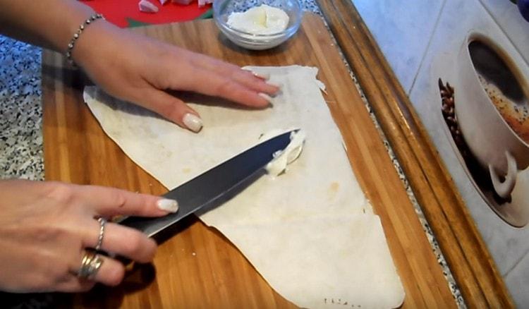 Graisser une partie de pain pita avec du fromage à la crème.