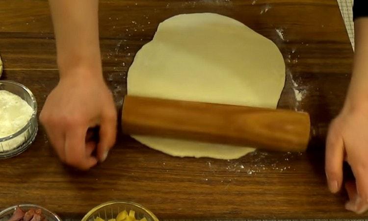 When the dough comes up, divide it in half and roll out each part with a rolling pin.