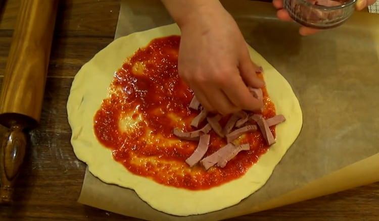 En la mitad de la masa untada con salsa, ponga la salchicha en rodajas.