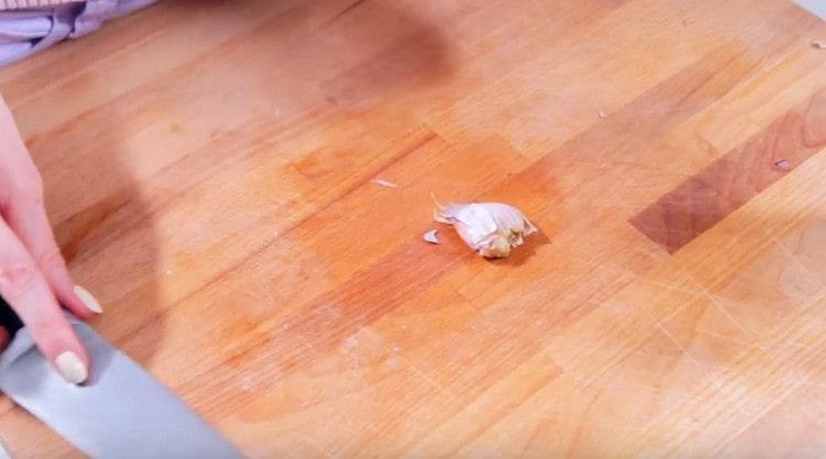 Peel the garlic clove and crush it with a knife.