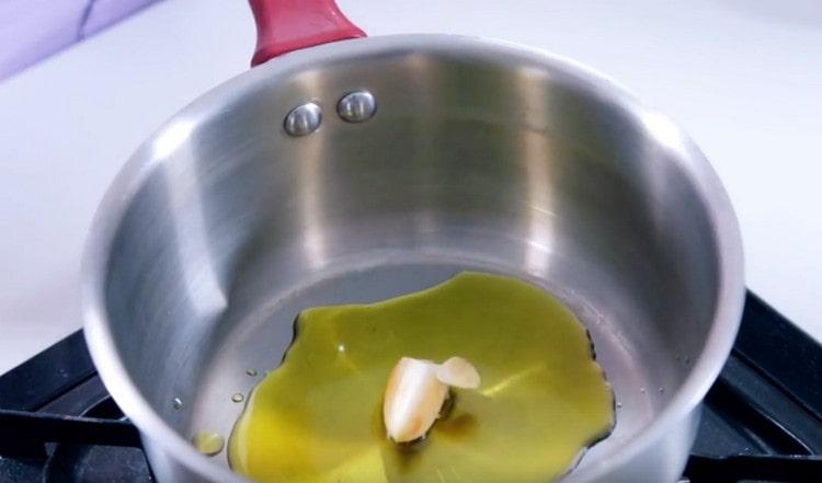 Pour olive oil into the stewpan and put the garlic in it.