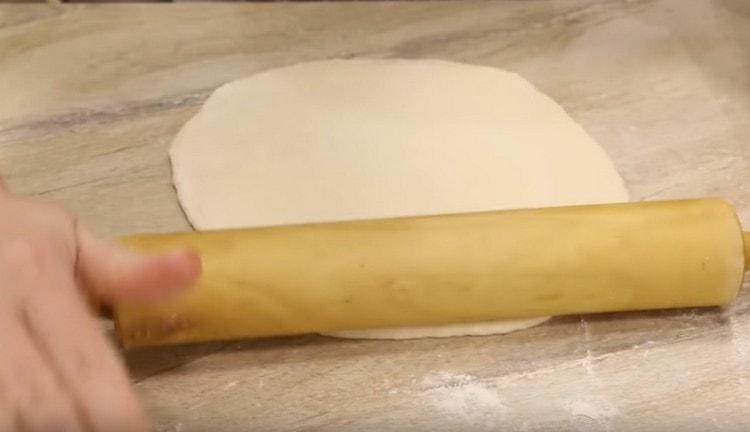 Roll out a piece of dough with a rolling pin.