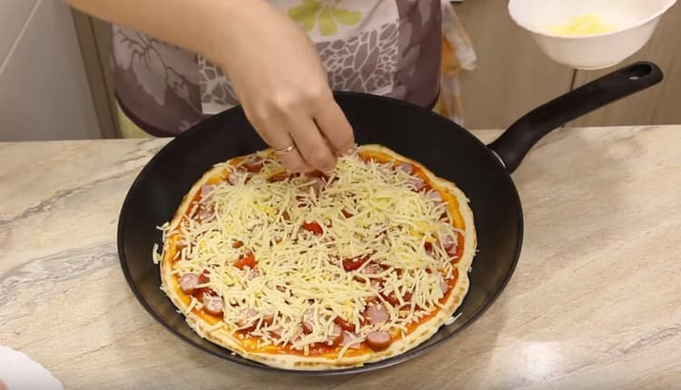 Espolvorea pizza con queso.
