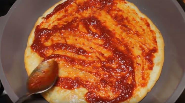 Immediately grease our pizza base with tomato sauce.