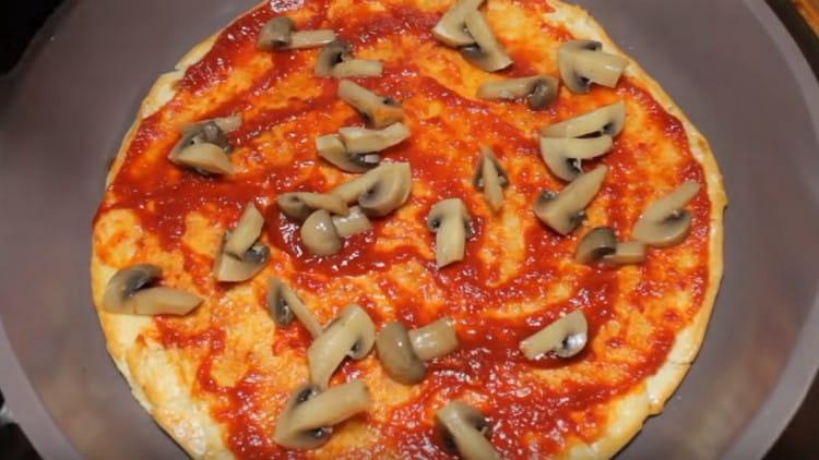 Nous répandons des champignons sur une pizza.