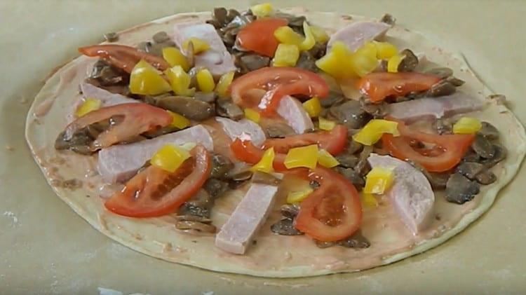Spread the sausage slices. mushrooms, peppers and tomatoes on the dough.