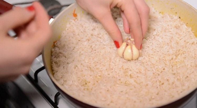 En el arroz en el centro de la sartén pegamos una cabeza de ajo.