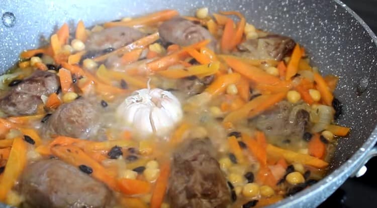 Extendemos la carne en la sartén, así como la cabeza de ajo.