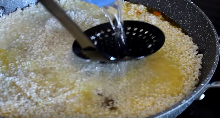Distribute the rice evenly over the pan, fill it with water.