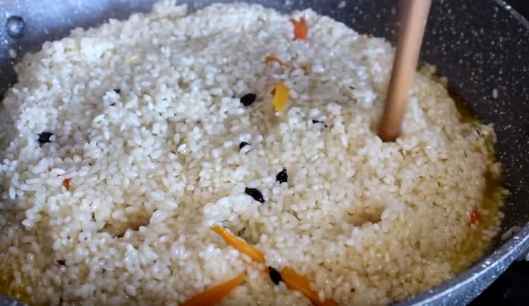 Kad voda djelomično ispari, skupite rižu klizačem i napravite rupe u njoj.