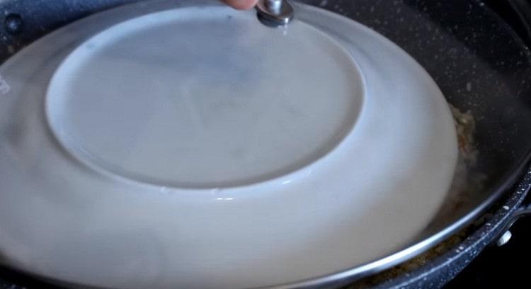 We cover the dish with a plate, and then another lid and continue to simmer over low heat.