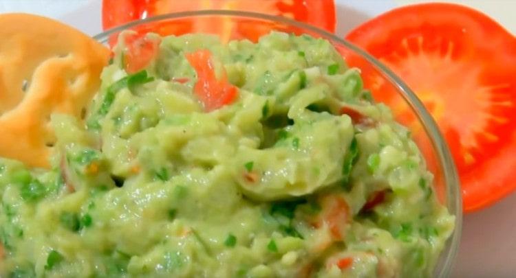 Guacamole sauce, prepared according to the classic recipe with avocado, can be served with various snacks.