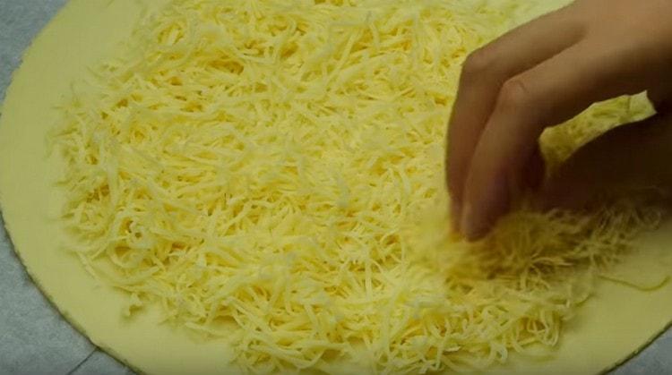 We spread the grated cheese on the base prepared for the pie.