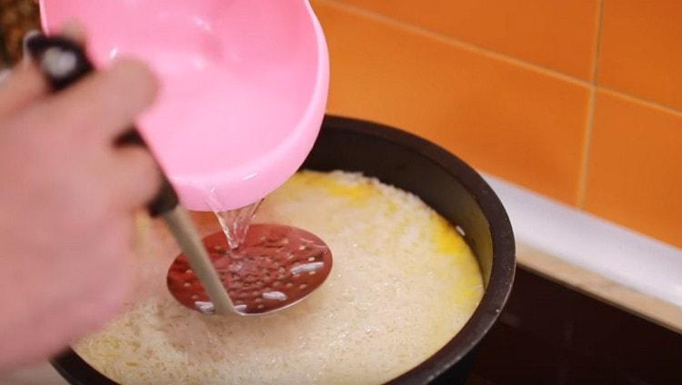 on étale le riz et on le distribue uniformément sur la viande avec les légumes, on ajoute de l'eau.