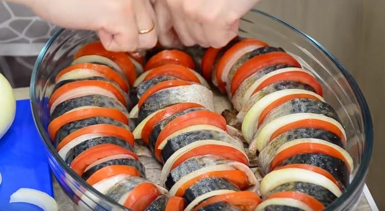 En forma engrasada con aceite vegetal, coloque los trozos de pescado, alternando con rodajas de cebolla y tomate.