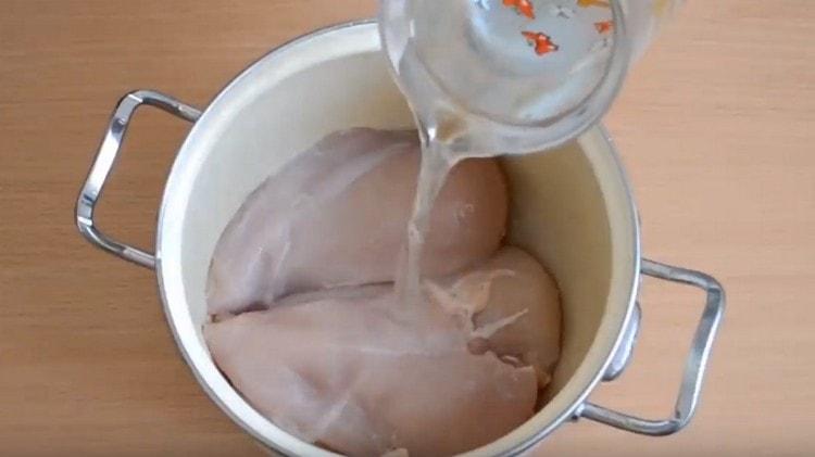 On étale le filet de poulet dans une casserole, on le remplit d'eau.