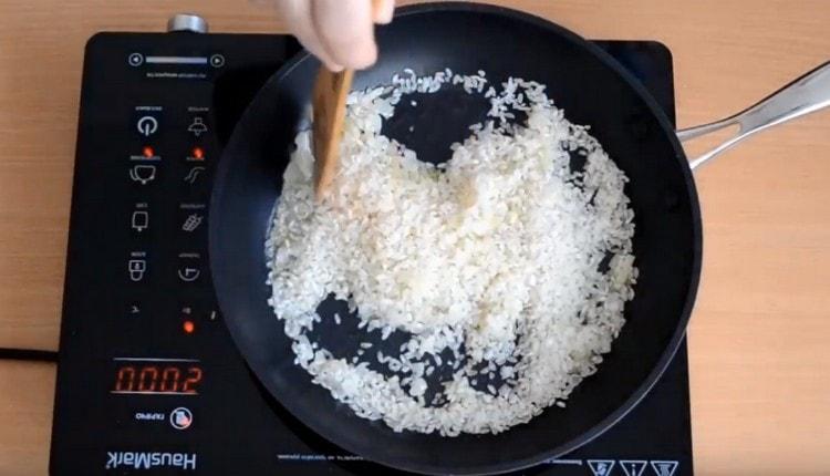 Fry rice with onions, stirring it.