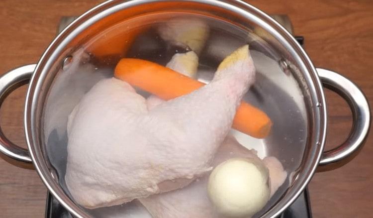 Versez de l'eau dans la casserole, y déposez les cuisses de poulet, ainsi que les oignons et les carottes entières.