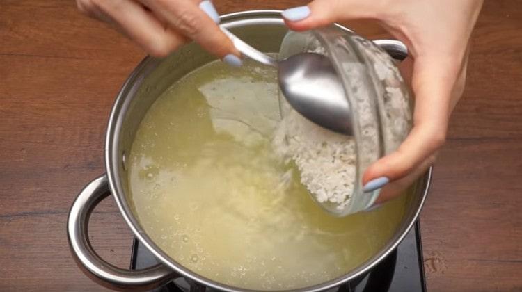 Nous répandons les pommes de terre et le riz lavé dans le bouillon.