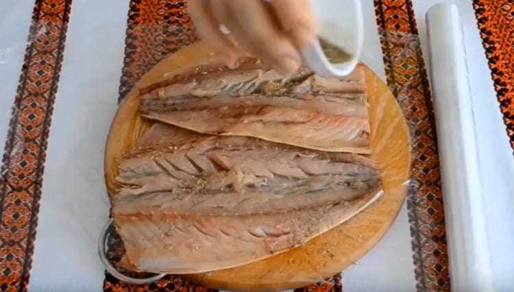 We lay out the fish fillet on cling film, sprinkle with salt and spices.