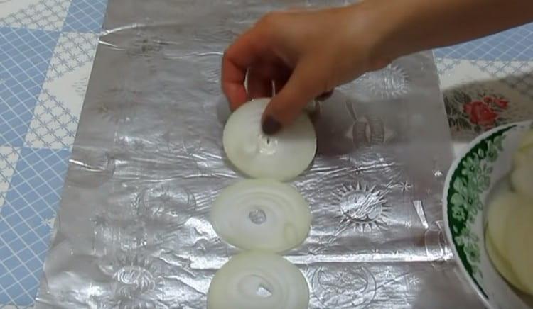Nous mettons des rondelles d'oignon sur le papier d'aluminium.