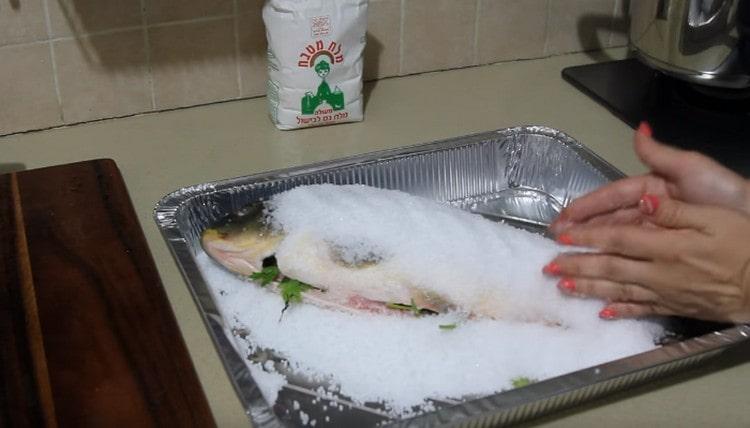 Sprinkle salt on top of the fish, distribute the salt with your hands so that it completely covers the carcass.