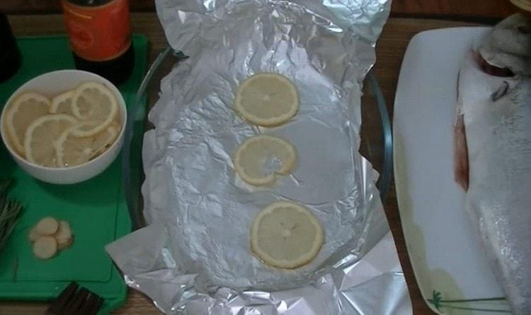 Cubra la fuente para hornear con papel de aluminio, engrase con aceite vegetal y esparza unas rodajas de limón.