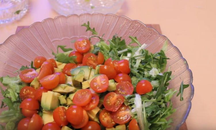Pon los tomates picados y el aguacate en un plato grande de rúcula.