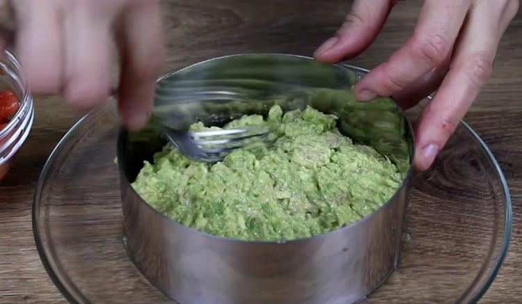 The first layer of the dish is mashed avocado.